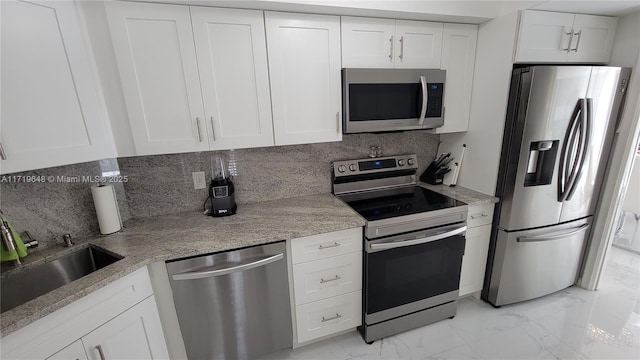 kitchen featuring sink, decorative backsplash, light stone countertops, white cabinetry, and stainless steel appliances