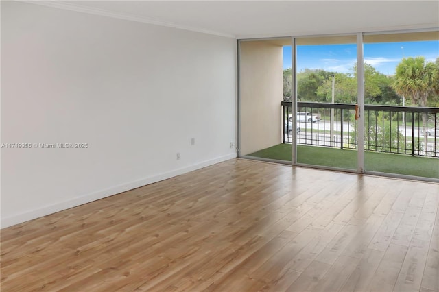 spare room with crown molding, light hardwood / wood-style flooring, and a wall of windows