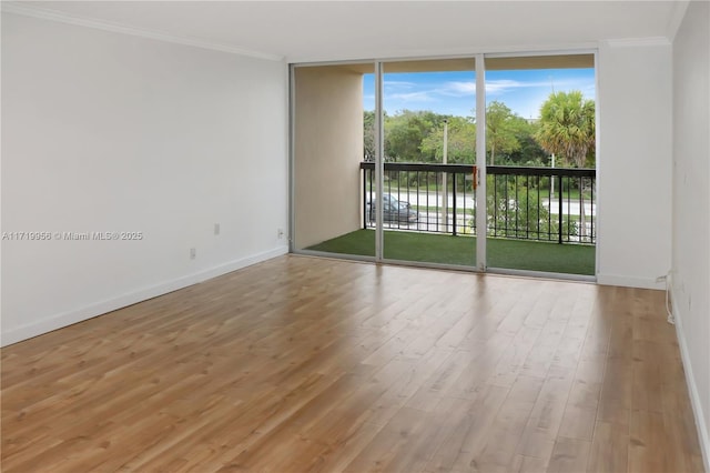 spare room with hardwood / wood-style floors, expansive windows, and ornamental molding