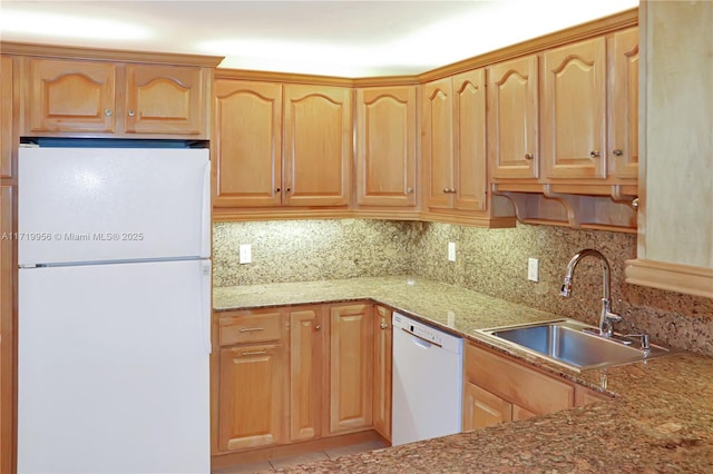 kitchen featuring light stone countertops, white appliances, backsplash, and sink