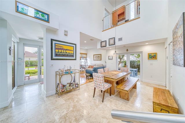 dining area with a towering ceiling and french doors