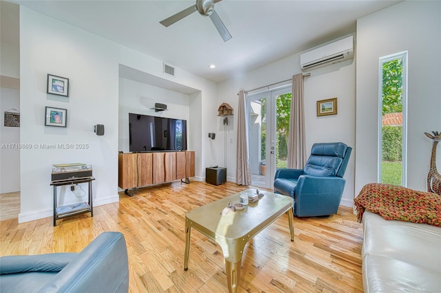 living room with ceiling fan, light wood-type flooring, french doors, and a wall mounted AC