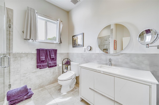 bathroom with vanity, tile patterned floors, toilet, tile walls, and a shower with shower door