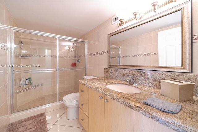 bathroom with vanity, tile patterned floors, toilet, tile walls, and an enclosed shower