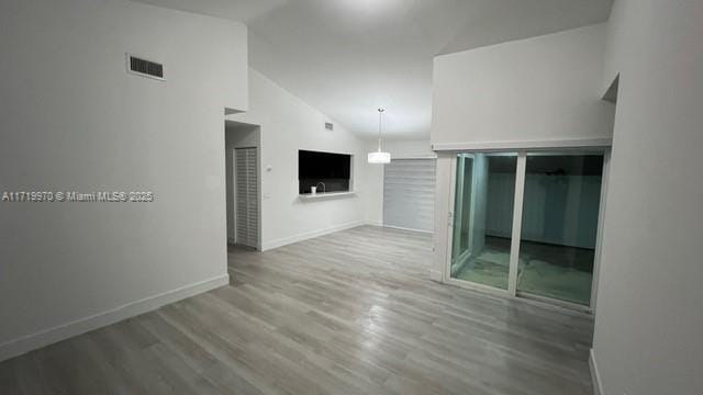 unfurnished living room featuring wood-type flooring and high vaulted ceiling