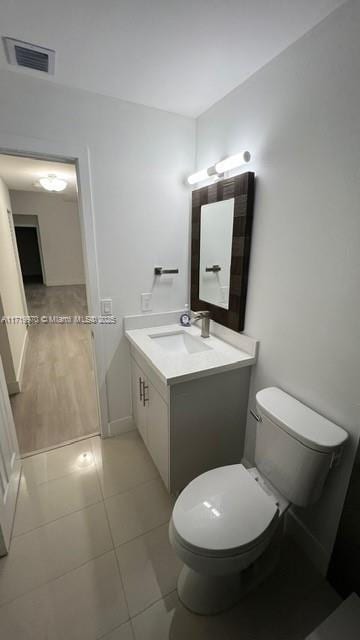 bathroom with tile patterned flooring, toilet, vanity, visible vents, and baseboards