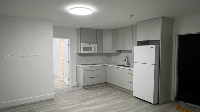 kitchen featuring sink, gray cabinetry, white appliances, and light hardwood / wood-style flooring