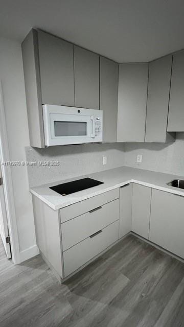 kitchen featuring hardwood / wood-style flooring, sink, and black electric cooktop