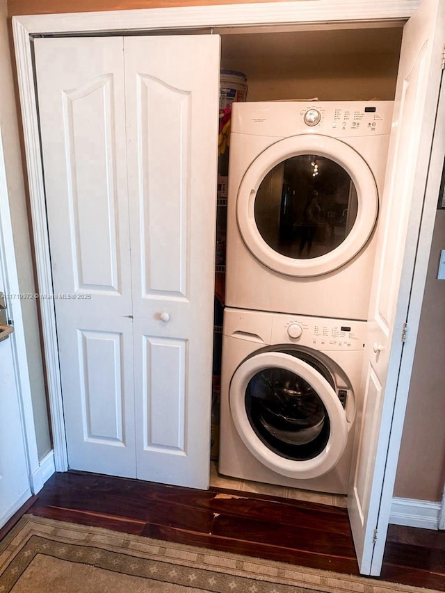 laundry room with stacked washer and dryer and dark wood-type flooring