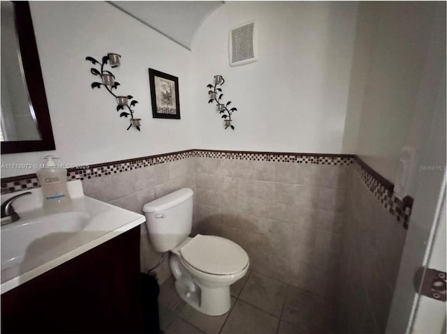 bathroom with tile patterned flooring, vanity, tile walls, and toilet