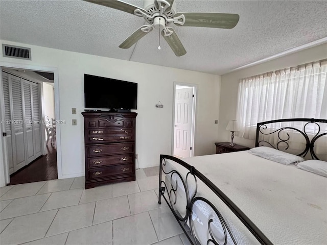 tiled bedroom featuring ceiling fan and a textured ceiling