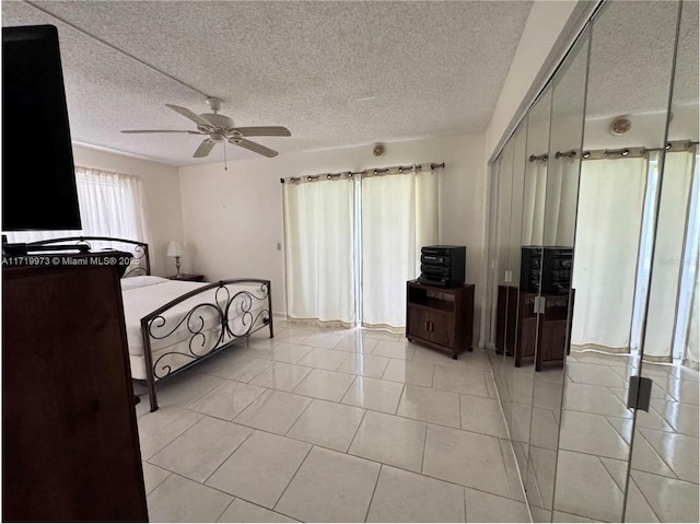 tiled bedroom featuring ceiling fan, a closet, and a textured ceiling