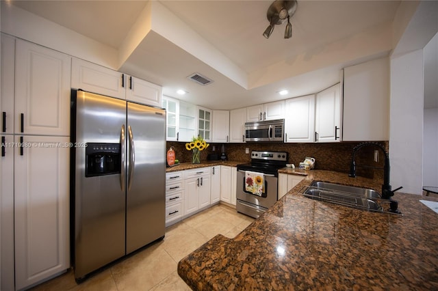 kitchen featuring tasteful backsplash, dark stone counters, stainless steel appliances, sink, and white cabinetry