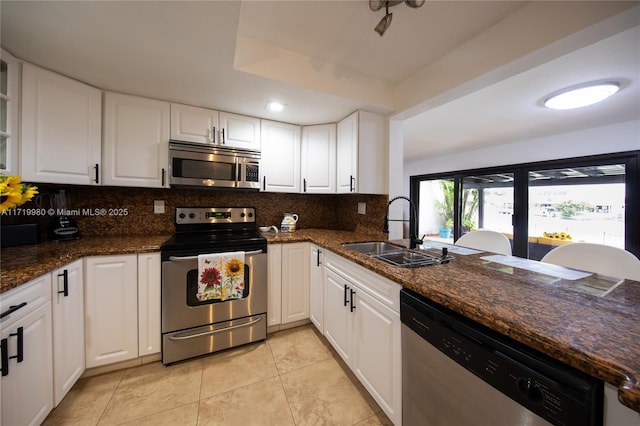 kitchen with dark stone counters, white cabinets, sink, light tile patterned floors, and appliances with stainless steel finishes