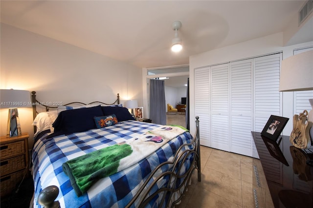 tiled bedroom featuring ceiling fan and a closet