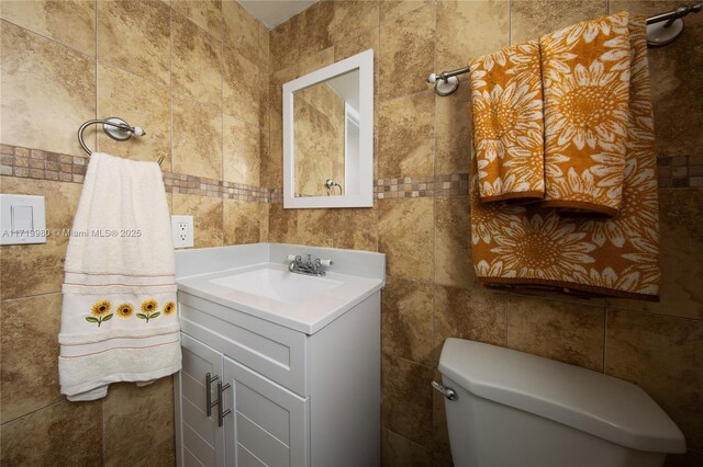 bathroom with vanity, toilet, and tile walls