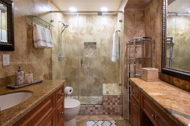 bathroom featuring vanity, toilet, tile walls, and walk in shower