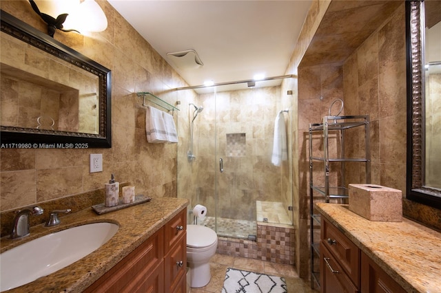 bathroom with vanity, tile walls, tile patterned flooring, toilet, and a shower with shower door