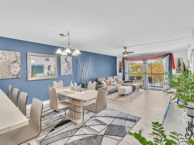 dining room featuring wood finished floors and ceiling fan with notable chandelier