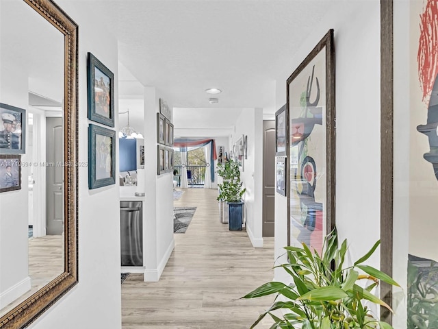 corridor featuring light hardwood / wood-style flooring and a notable chandelier