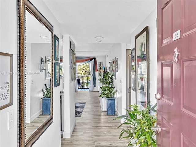 hall with light wood-type flooring and baseboards