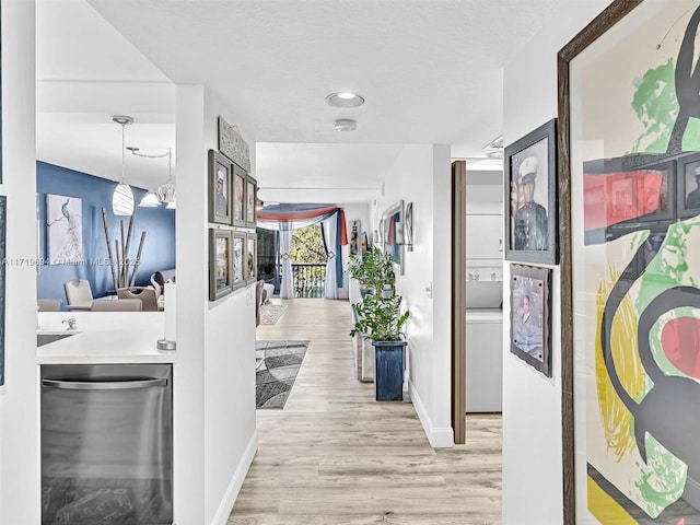 corridor featuring a textured ceiling, baseboards, and wood finished floors