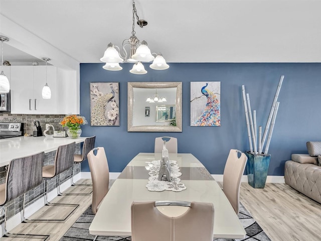 dining room with a chandelier, light wood-style flooring, and baseboards