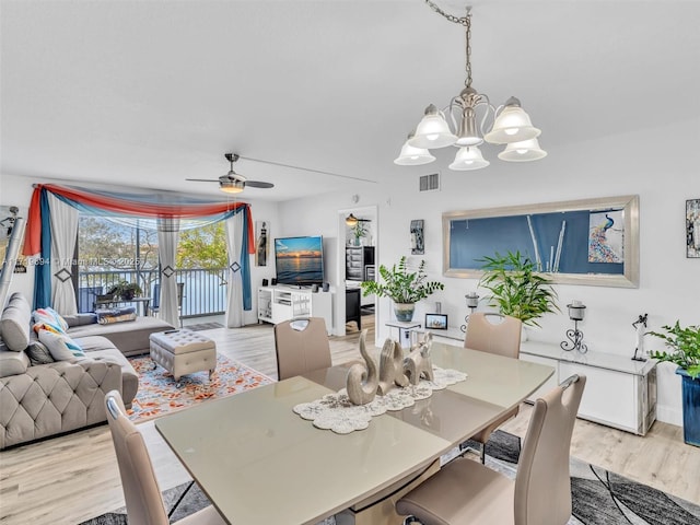 dining space with ceiling fan with notable chandelier, light wood finished floors, and visible vents