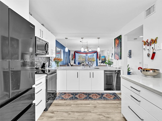 kitchen featuring range with electric cooktop, visible vents, light countertops, freestanding refrigerator, and dishwasher