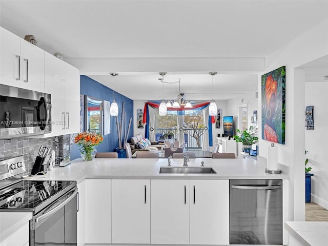 kitchen featuring a wealth of natural light, light countertops, appliances with stainless steel finishes, white cabinetry, and a sink