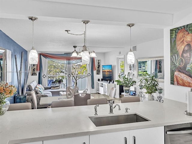 kitchen featuring visible vents, dishwasher, open floor plan, hanging light fixtures, and a sink