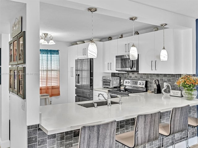 kitchen with a toaster, stainless steel appliances, backsplash, a sink, and a peninsula