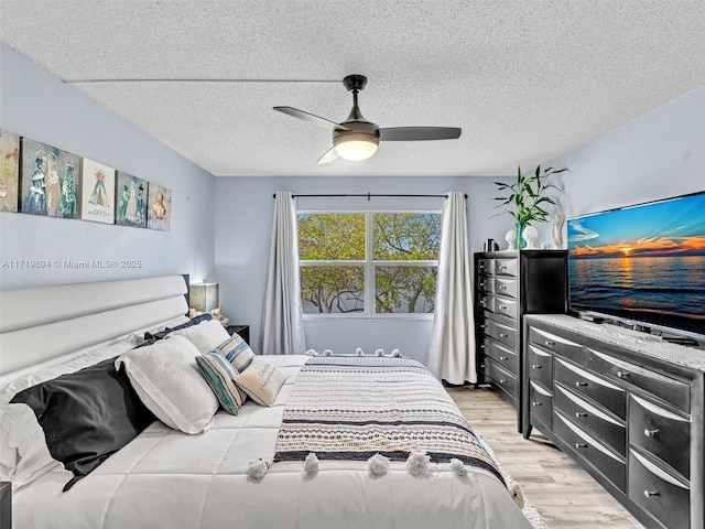 bedroom featuring a textured ceiling, light wood-style flooring, and a ceiling fan