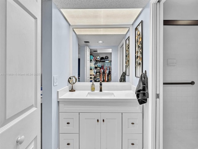 full bath with a stall shower, a walk in closet, visible vents, and vanity