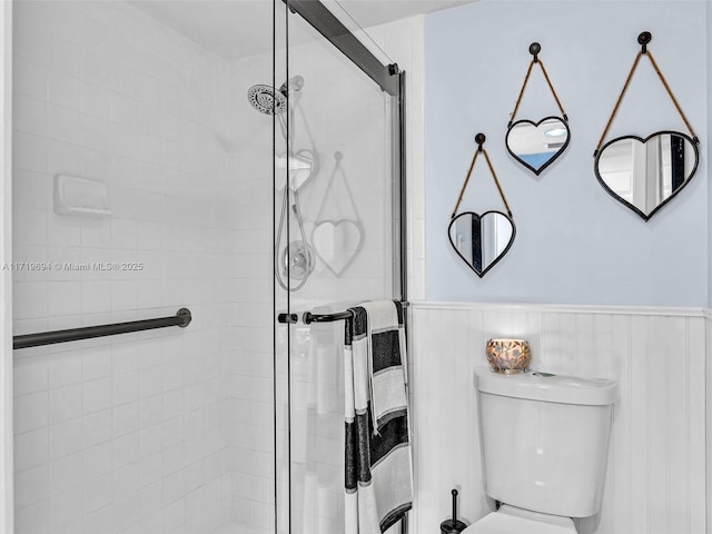 bathroom featuring a wainscoted wall, a shower stall, and toilet