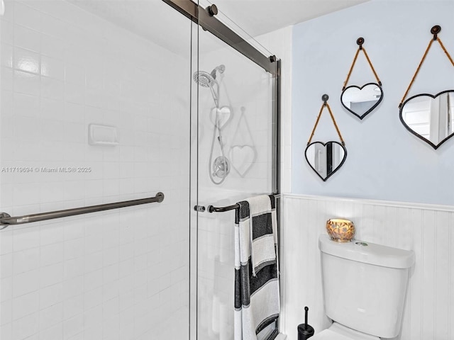 full bathroom with wainscoting, a shower stall, and toilet