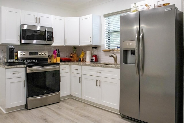 kitchen featuring tasteful backsplash, light stone counters, white cabinets, and stainless steel appliances