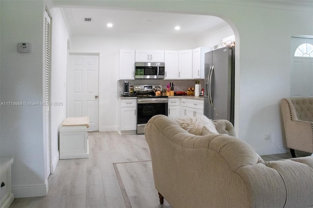 kitchen with light hardwood / wood-style floors, white cabinetry, appliances with stainless steel finishes, and tasteful backsplash