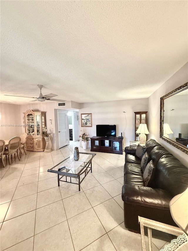 living room featuring light tile patterned floors, a textured ceiling, and ceiling fan