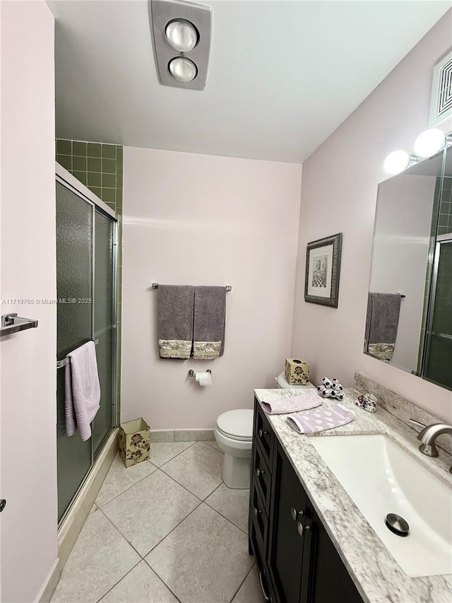 bathroom with tile patterned floors, a shower with door, vanity, and toilet