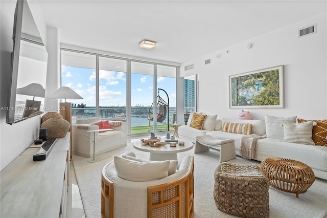 living room with a wealth of natural light, a water view, and a wall of windows