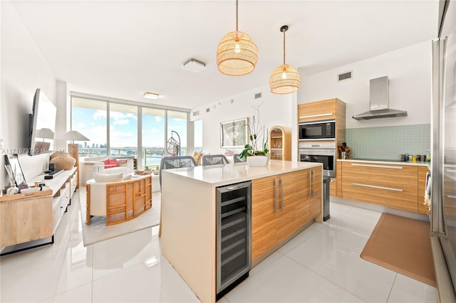 kitchen with black microwave, a center island, wall chimney range hood, wine cooler, and expansive windows