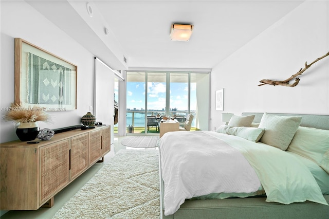 bedroom featuring access to outside, floor to ceiling windows, and a water view