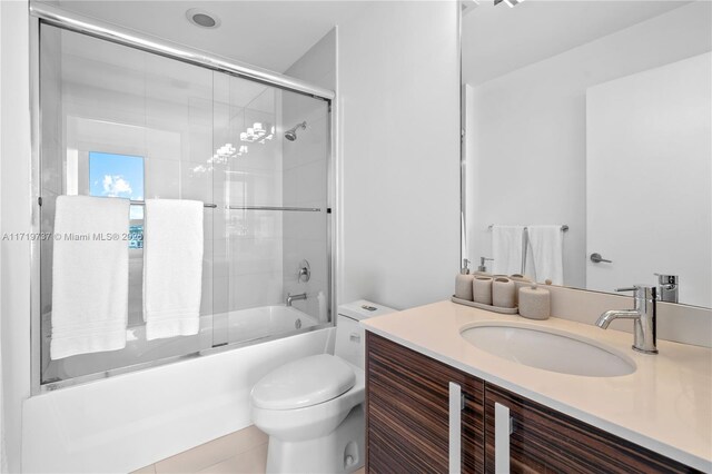 full bathroom with tile patterned flooring, vanity, bath / shower combo with glass door, and toilet