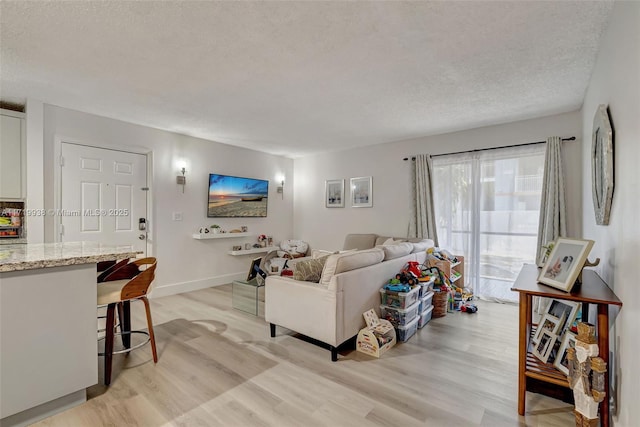 living room with a textured ceiling and light wood-type flooring