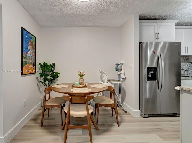 dining room featuring a textured ceiling and light hardwood / wood-style floors