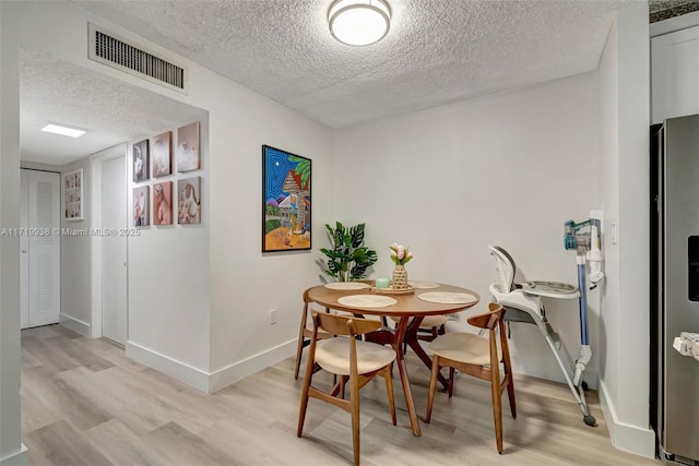 dining area with a textured ceiling and light wood-type flooring