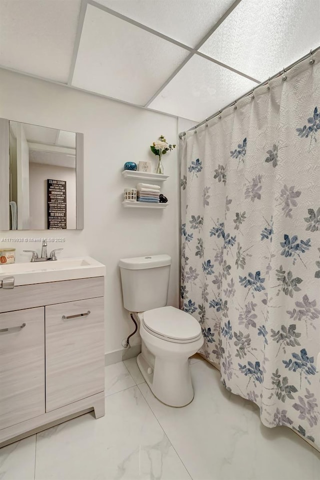 bathroom with a drop ceiling, toilet, and vanity