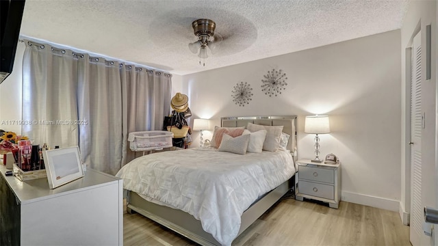 bedroom with ceiling fan, light hardwood / wood-style floors, a textured ceiling, and a closet