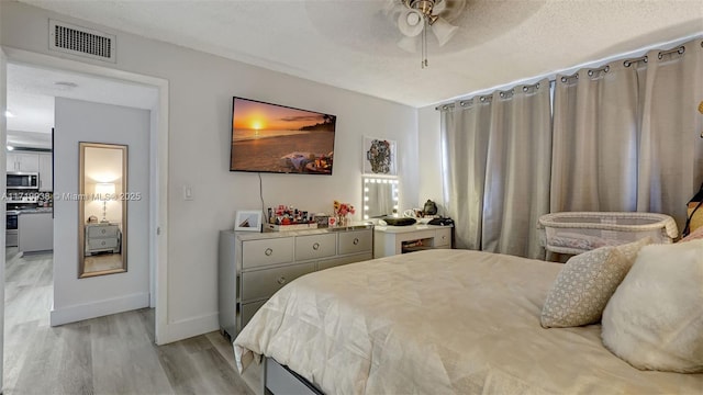 bedroom featuring ceiling fan, light hardwood / wood-style floors, and a textured ceiling